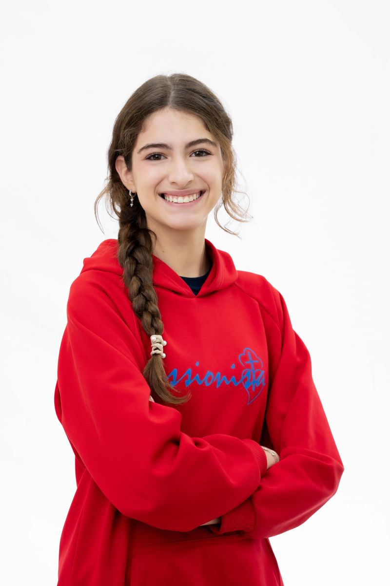 Aluna do Colégio Passionista NSM sorrindo de braços cruzados